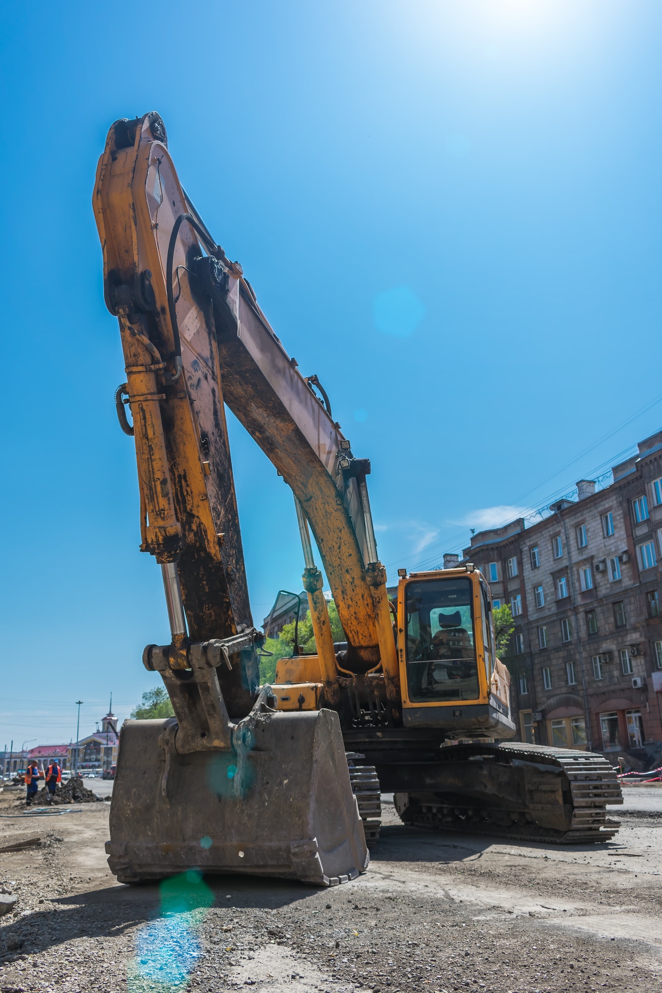 Excavator and his big bucket during the construction of the road against the backdrop of urban